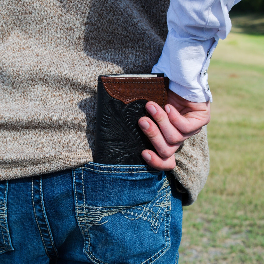 American West handcrafted western men’s leather wallet featuring hand tooled leather design and artisan craftsmanship carried in back pocket outdoors