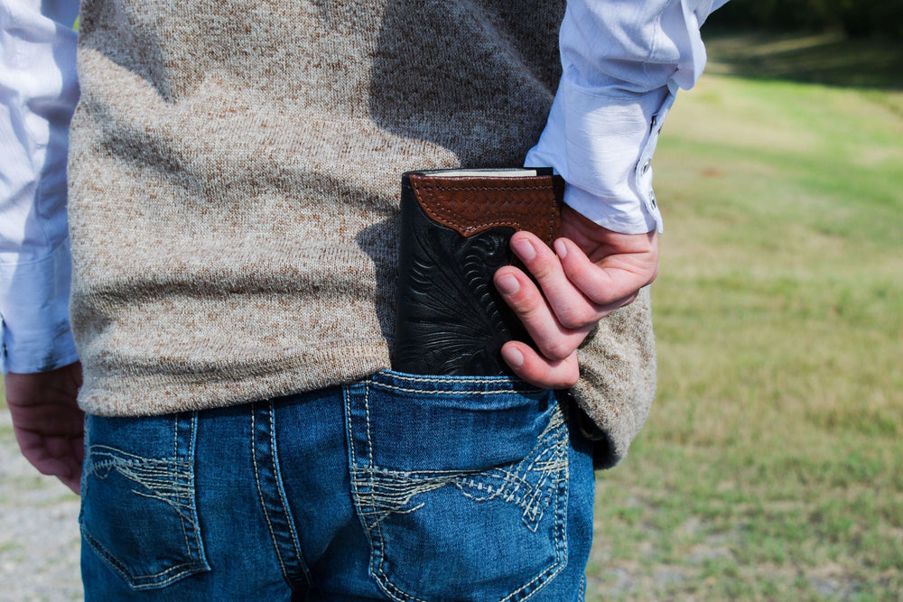 Lifestyle with model of Men's rodeo wallet in black with hand tooled leather accents