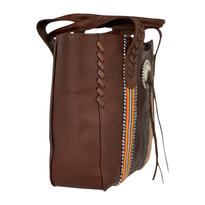 Side view of Maká Festive tote in brown with hand tooled leather, hand woven tapestry, and bolo concho with tassle