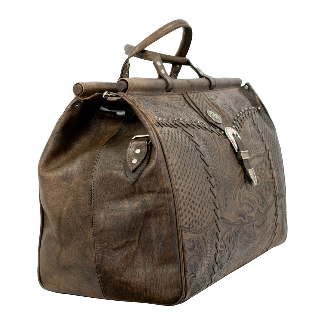 Side view of Classic Travel duffel bag in distressed charcoal brown with hand tooled leather and buckle set accents