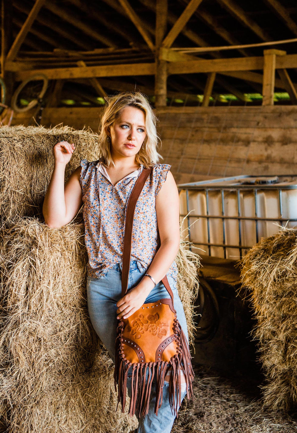 Lifestyle with model of Fringed Cowgirl crossbody in natural tan with hand tooled leather rose accents and fringe