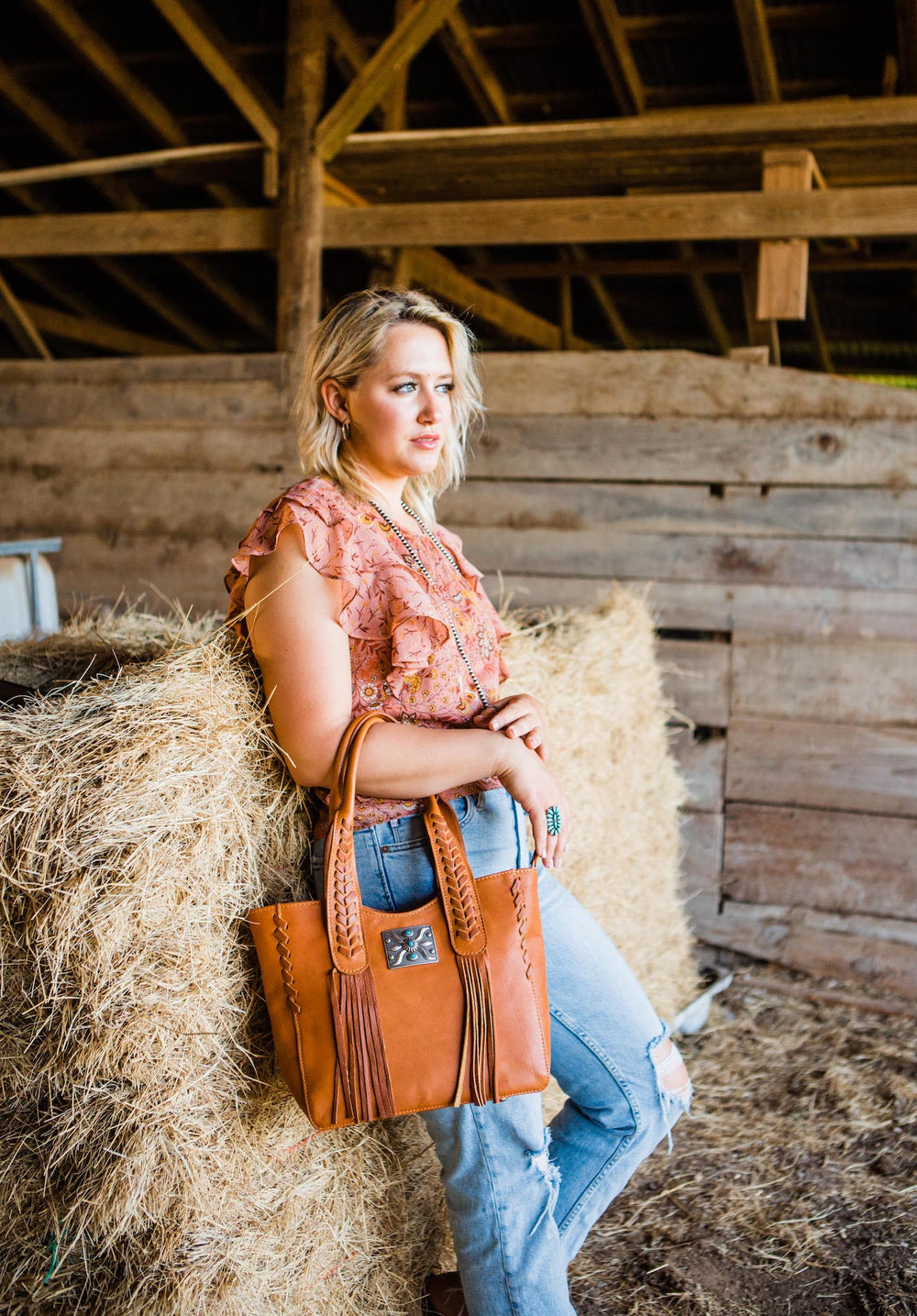 Lifestyle with model of Mohave Canyon tote in natural tan with concho and leather fringe accents
