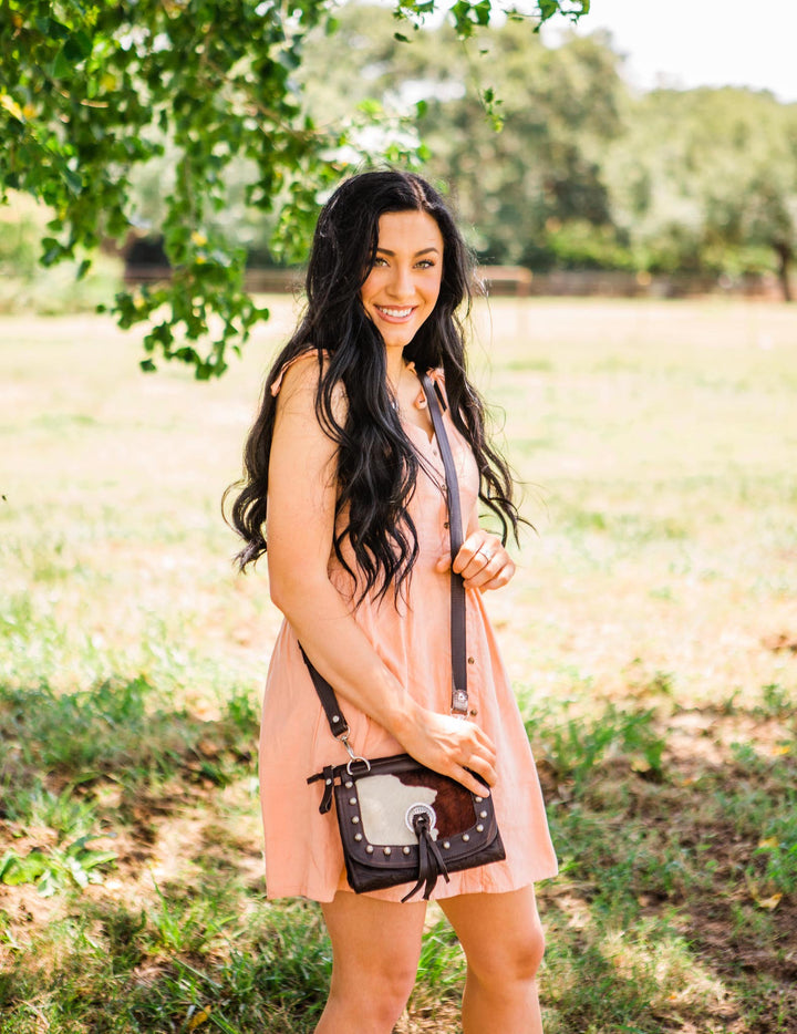 Lifestyle with model of Cow Town crossbody bag in pony with hair-on hide leather accents