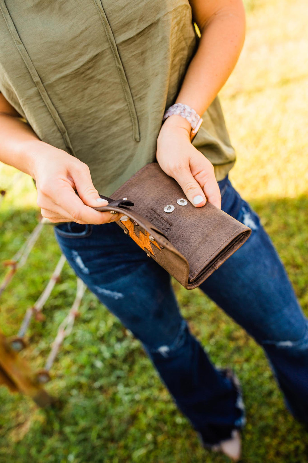 Lifestyle with model of Navajo Soul tri-fold wallet in distressed charcoal brown with hand tooled leather accents