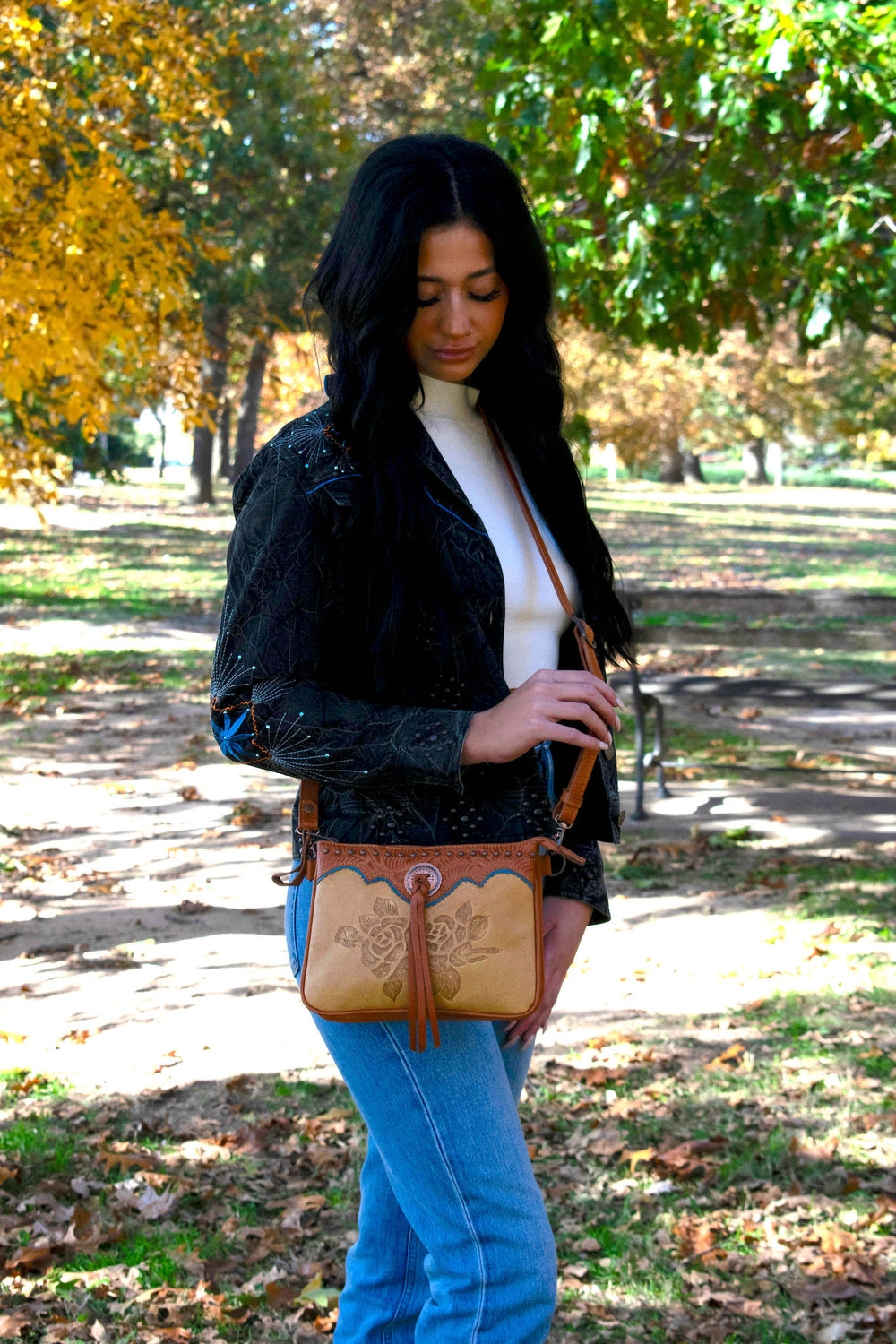 Lifestyle with model of Texas Rose multi-compartment crossbody in natural tan with hand tooled leather accents and bolo concho with tassel