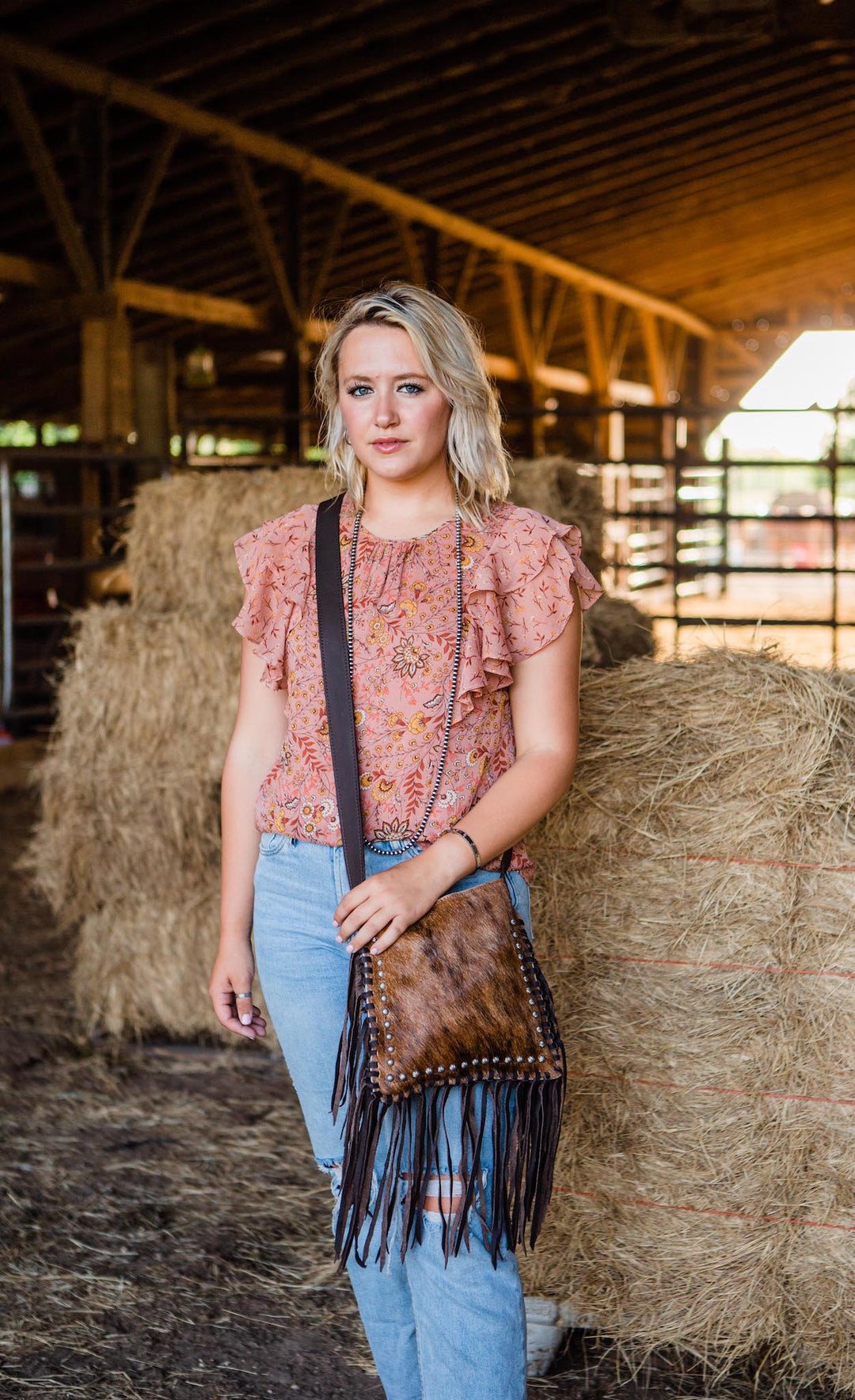 Lifestyle with model of Fringed Cowgirl crossbody in brindle with hair-on hide leather and fringe accents
