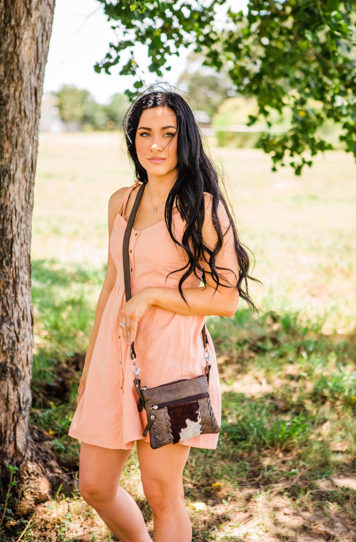 Lifestyle with model of Cowtown crossbody/hip bag in distressed charcoal brown with hair-on hide leather accents