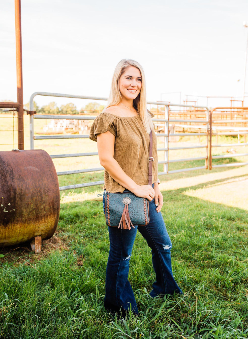 Lifestyle with model of Lariats and Lace multi-compartment Crossbody in dark turquoise with hand tooled leather, concho and tassel accents