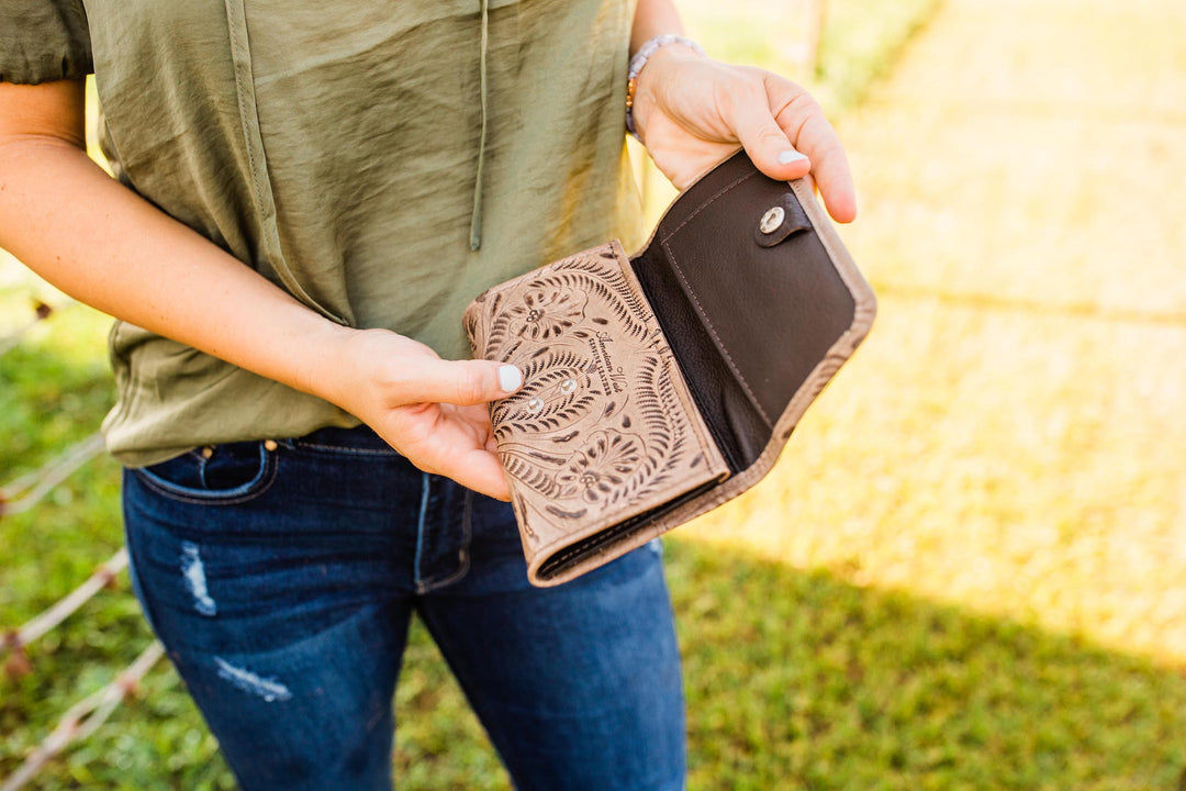 Lifestyle with model of Ladies tri-fold wallet in denim blue with hand tooled leather accents
