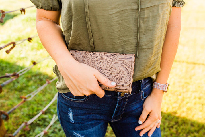 Lifestyle with model of Ladies tri-fold wallet in denim blue with hand tooled leather accents