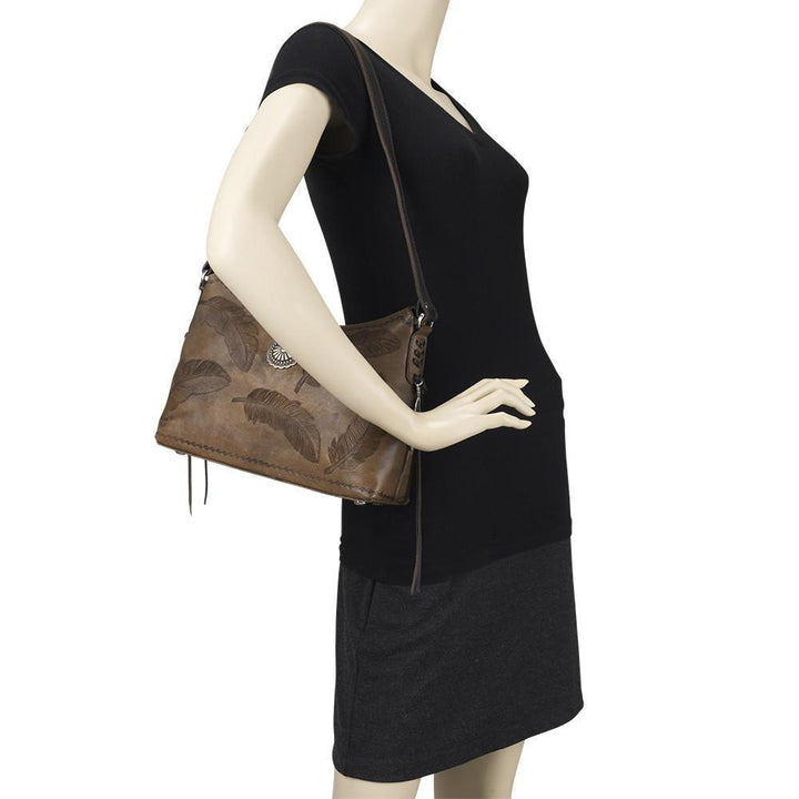 Sacred Bird shoulder bag in distressed charcoal brown leather with hand tooled feathers on mannequin