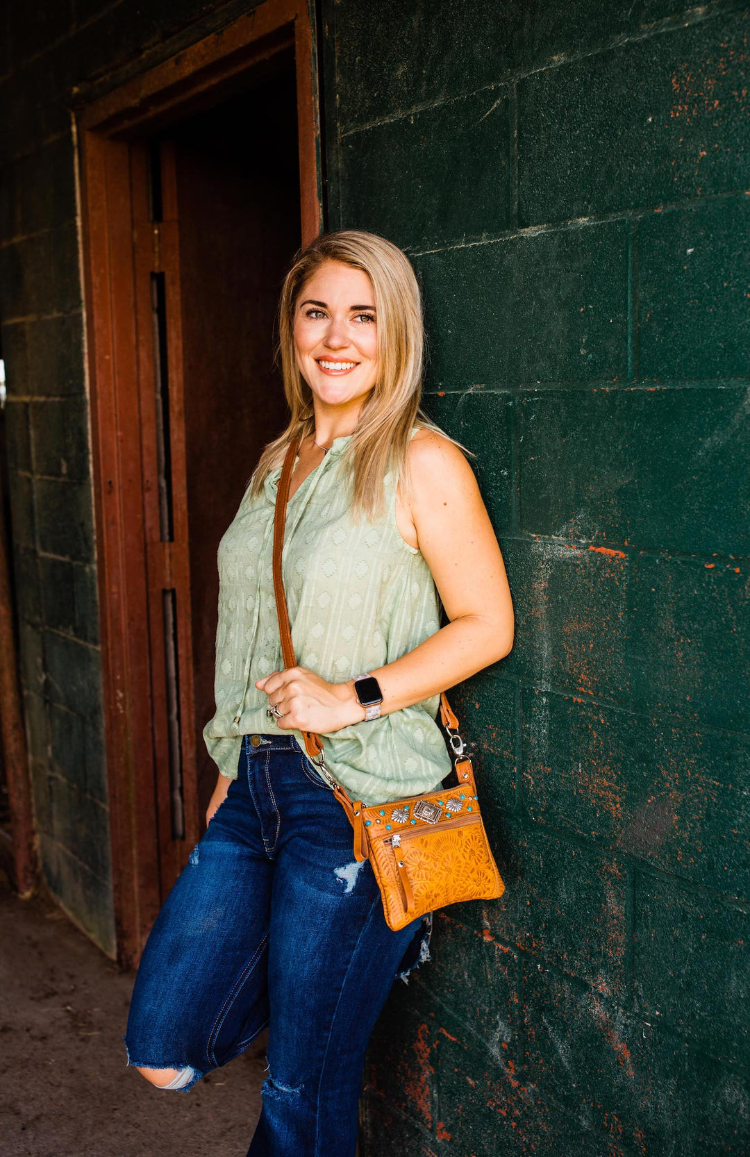 Lifestyle with model of Turquoise Mesa crossbody/hip bag in light tan with hand tooled leather accents