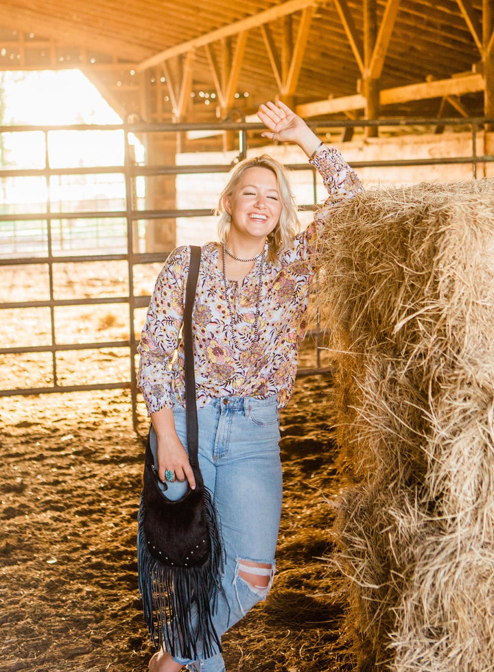 Lifestyle with model of Fringed Cowgirl crossbody in black with hand tooled leather and hair-on hide accents and fringe