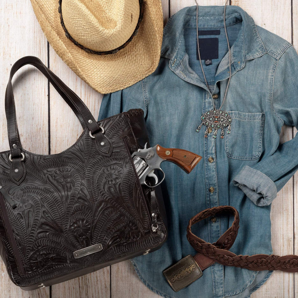 Flatlay of Annie's Secret conceal carry tote in denim blue with hand tooled leather accents and outfit