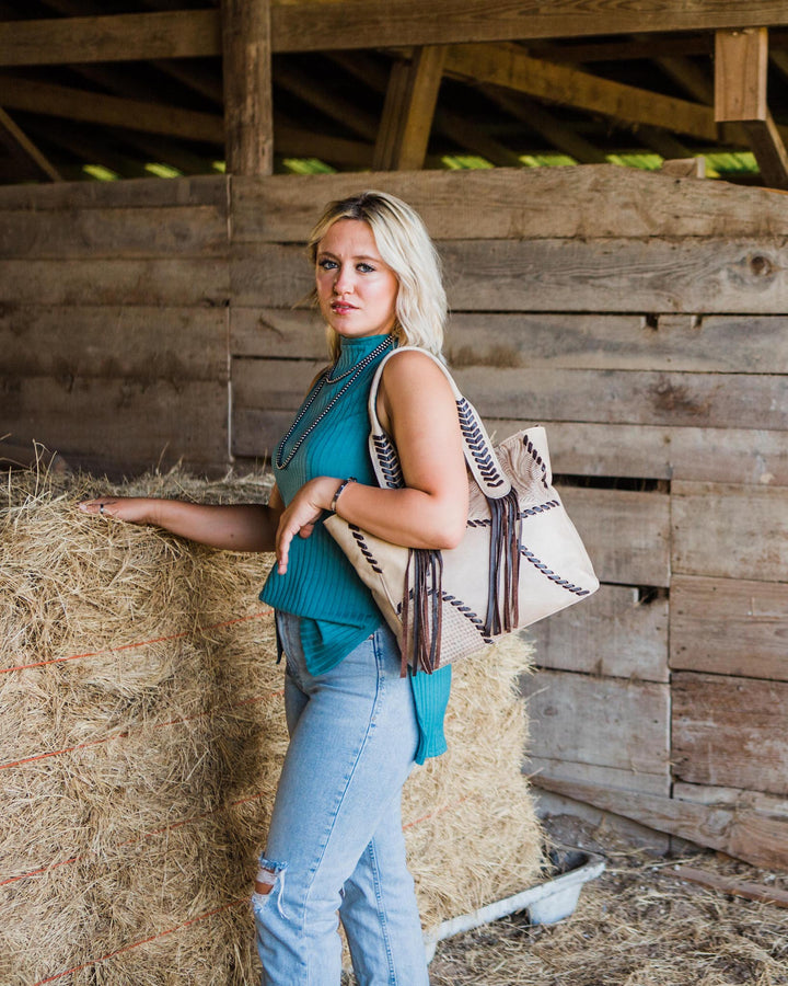 Lifestyle with model of Gypsy Patch tote in sand with hand tooled leather accents