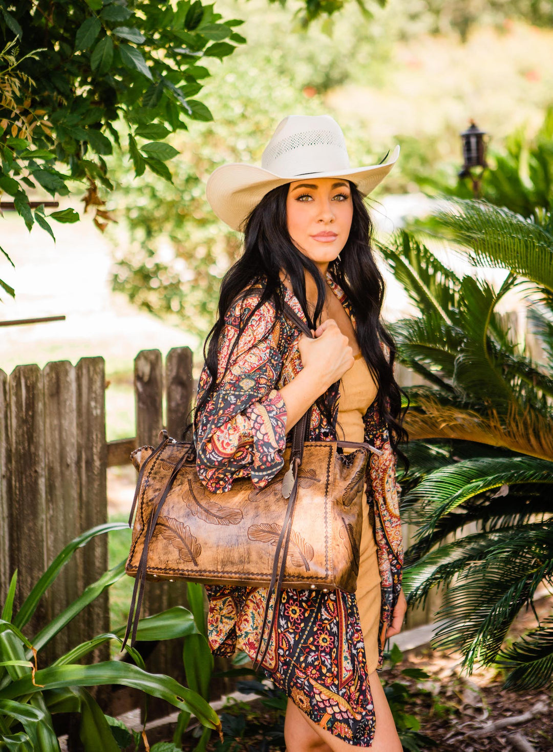 Lifestyle with model of Sacred Bird conceal carry tote in distressed charcoal brown leather with hand tooled feathers