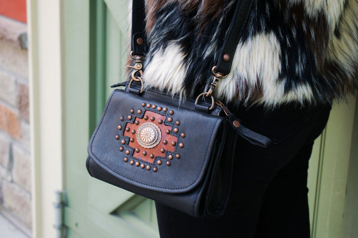 Lifestyle with model of Midnight Copper crossbody bag in black with hand tooled accents