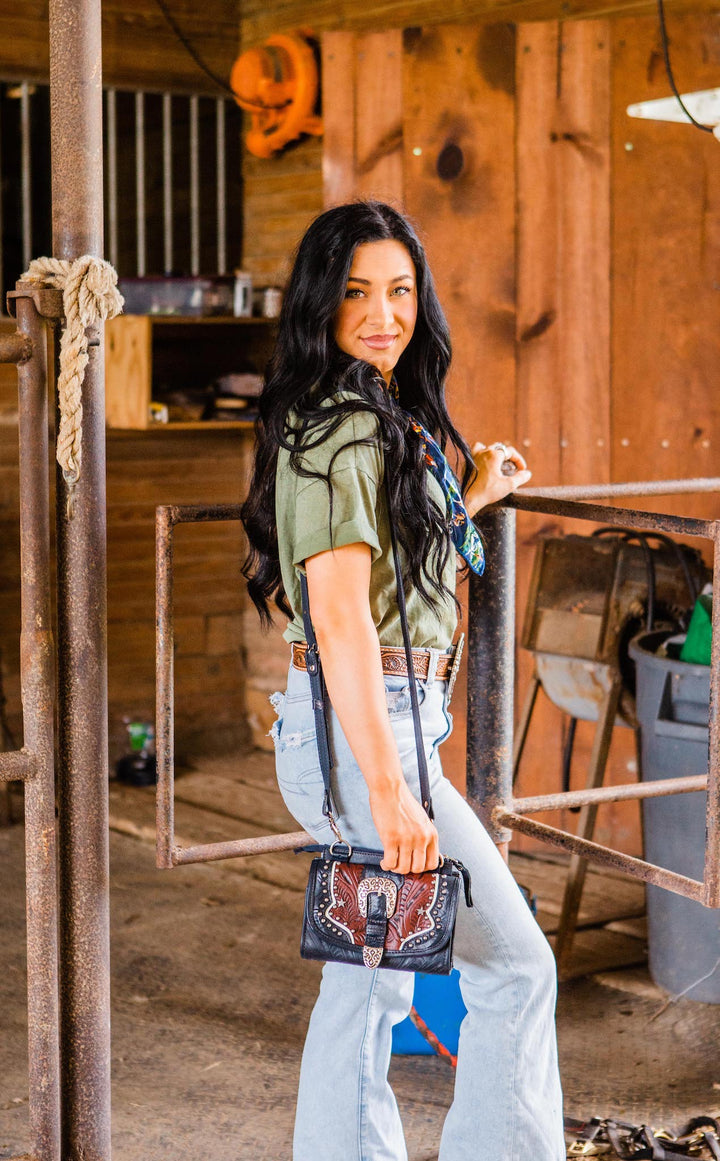Lifestyle with model of Texas Two Step crossbody bag in navy blue with hand tooled leather and buckle accents