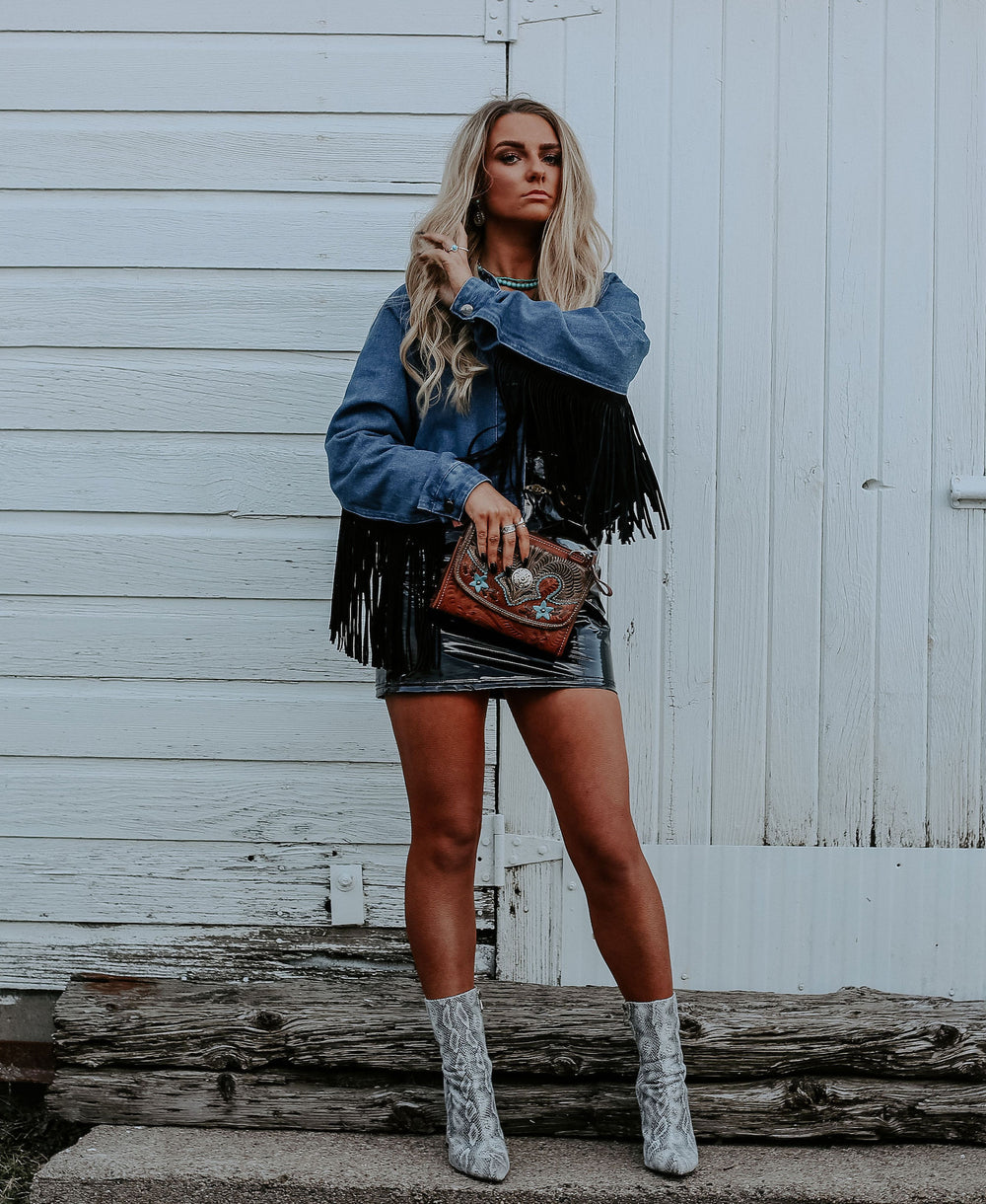 Lifestyle with model of Desert Wildflower crossbody bag in medium brown with hand tooled leather turquoise colored flower accents