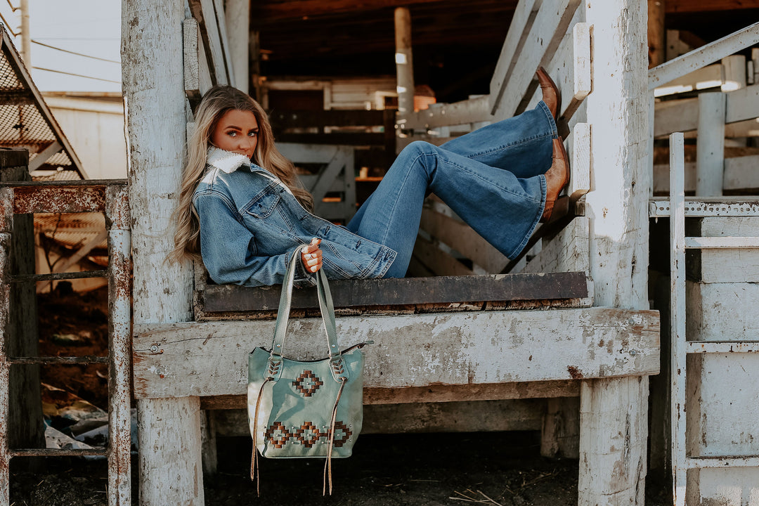 Lifestyle with model of Tribal Weave bucket tote in light turquoise with leather stitching accents