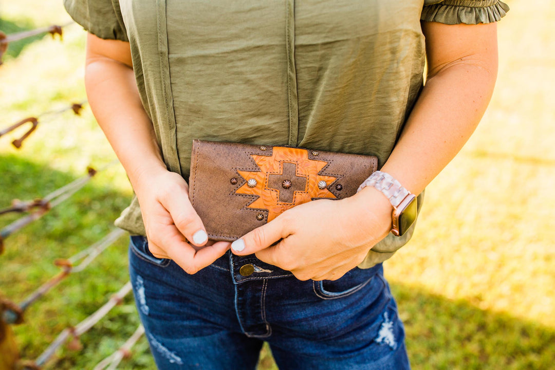 Lifestyle with model of Navajo Soul tri-fold wallet in distressed charcoal brown with hand tooled leather accents
