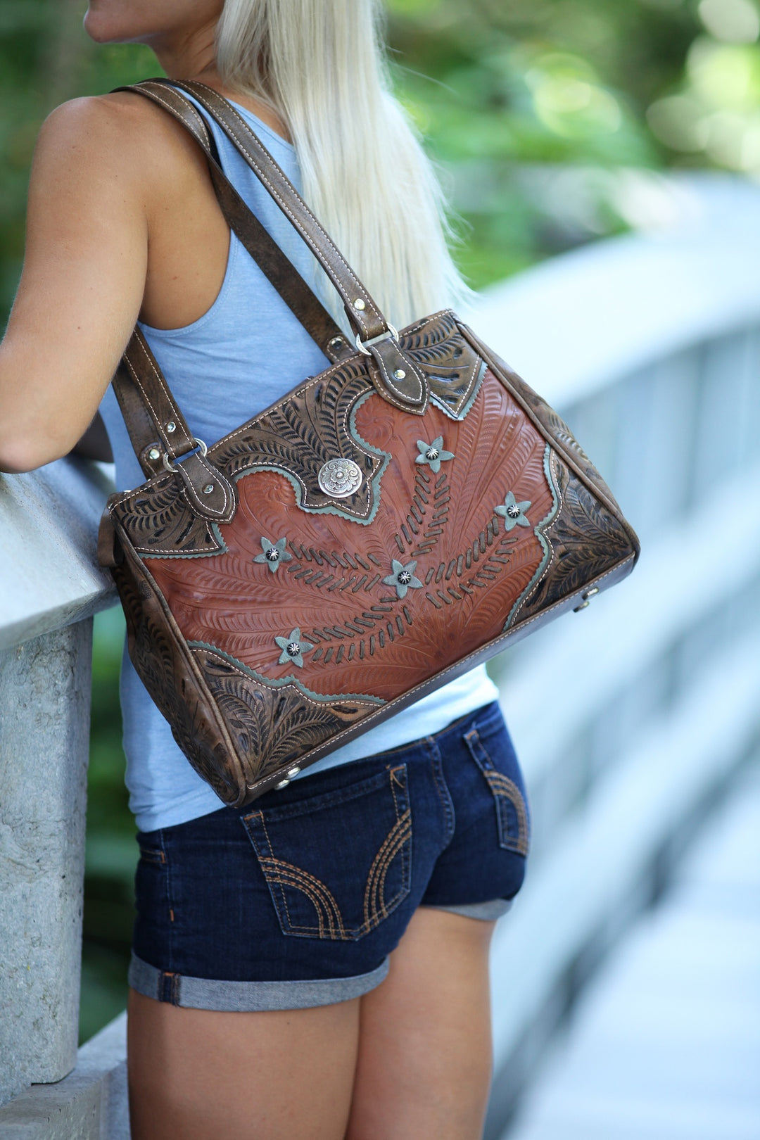 Lifestyle with model of Desert Wildflower multi-compartment organizer tote in natural tan with hand tooled leather cream colored flower accents