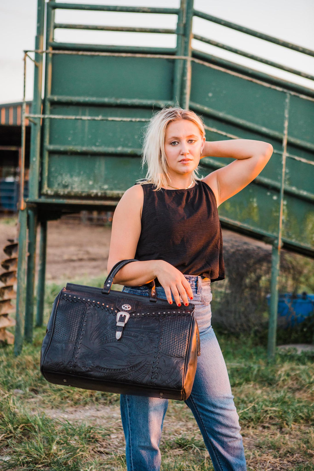 Lifestyle with model of Classic Travel duffel bag in black with hand tooled leather and buckle set accents