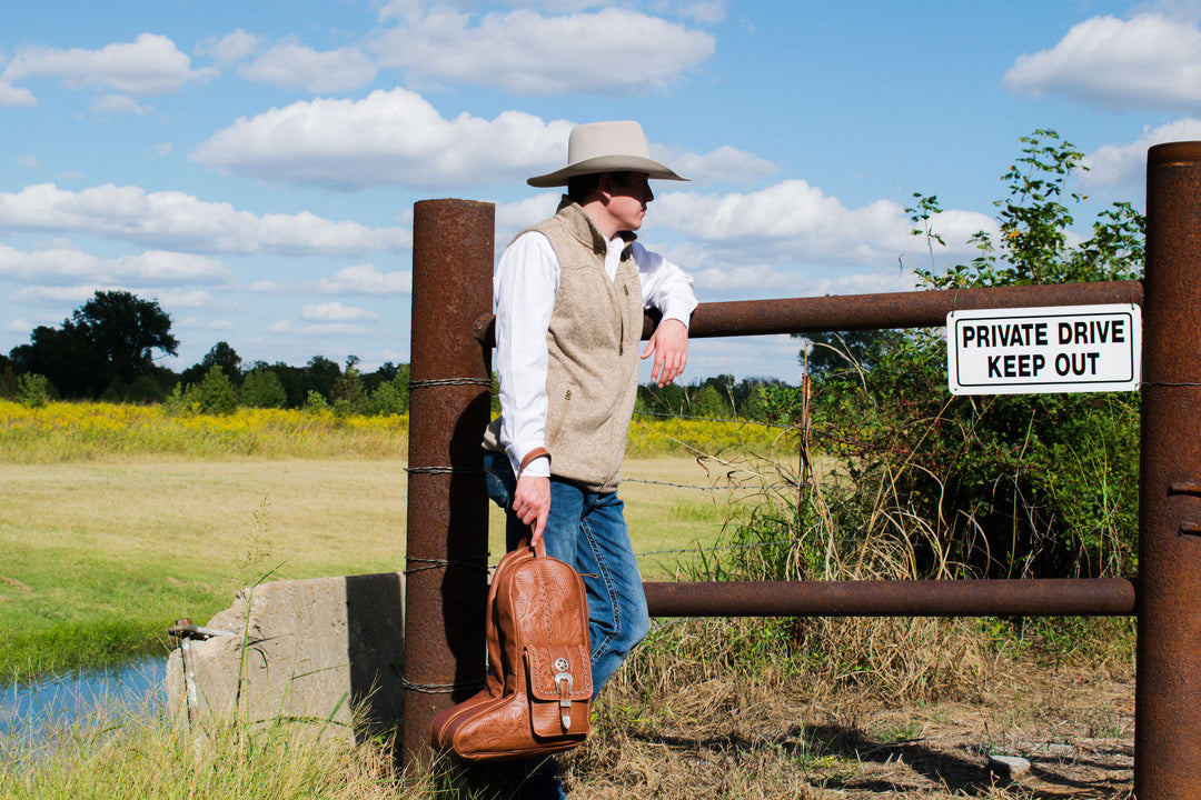 Lifestyle with model of Classic Travel boot bag in medium brown with hand tooled leather and buckle set accents