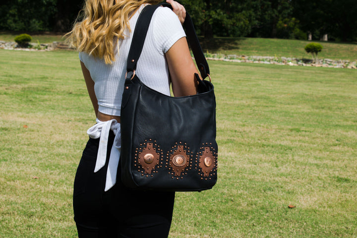 Lifestyle with model of Midnight Copper conceal carry shoulder bag in black with hand tooled accents